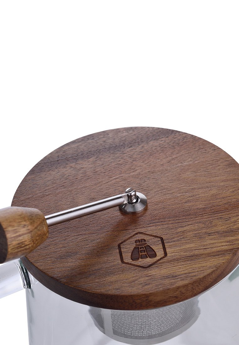 Glas French Press mit einem runden Holzdeckel, einem Edelstahlgriff und einem sechseckigen Logo. Das Holz hat eine glatte Textur und eine natürliche Maserung.