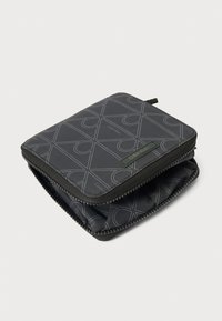 Čierna peňaženka so zipsom s geometrickým vzorom, vyrobená z odolnej tkaniny, s textúrovaným povrchom a značkovou štítkou na prednej strane.