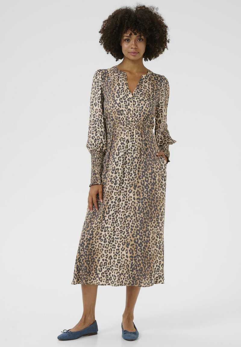 Leopard print dress with long sleeves, v-neckline, and elastic waistband. Soft fabric with slight sheen, knee-length, paired with blue flats.