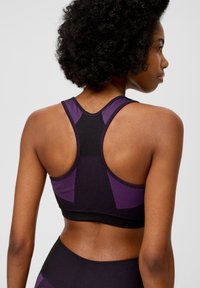 Sport-BH in Schwarz mit lila Akzenten, ausgestattet mit einem Racerback-Design, gerippter Textur und glattem Stoff. Keine sichtbaren Beschläge oder Verschlüsse.