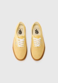 Yellow suede sneakers with white laces, rounded toe, and gum rubber sole. Features Vans logo on the tongue and classic low-top design.