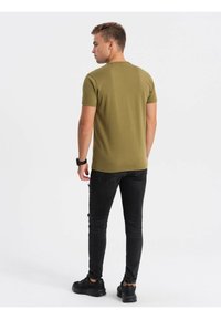 Olivi vihreä lyhythihainen paita, slim fit, pyöreä kaula-auko, yhdistetty mustiin revittyihin skinny-farkkuihin ja mustiin lenkkareihin. Yksinkertainen ja siisti muotoilu.