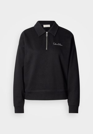 Black pullover top with a zippered front, collar, and long sleeves. Features embroidered brand name in white on the chest. Soft fabric texture.