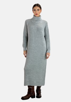 Graues geripptes Strickkleid mit Rollkragen, langen Ärmeln und knielanger Länge, kombiniert mit braunen Stiefeletten mit Schnallen und Riemen. Mäßige Textur.