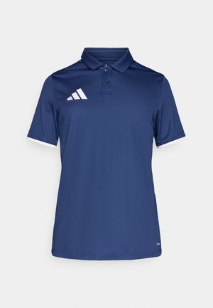 Μπλε ναυτικού πόλο πουκάμισο από λείο ύφασμα, με γιακά, κοντά μανίκια και λευκές λεπτομέρειες στις άκρες των μανικιών. Λογότυπο με τρεις λευκές ρίγες.