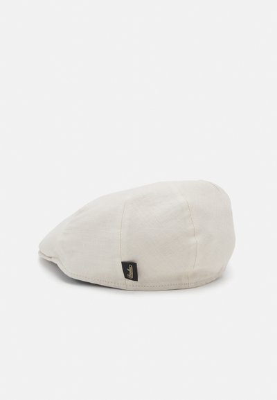 Lys beige caps laget av strukturert stoff med en buet skjerm. Har en liten svart etikett på siden. Myk og strukturert design.