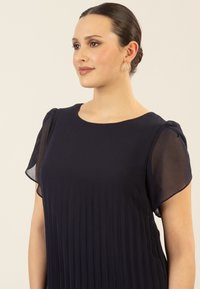 Marineblaues Kleid mit kurzen transparenten Ärmeln, plissierter Textur, Rundhalsausschnitt und glattem Stoff, der eine lockere Passform und eine elegante Silhouette bietet.
