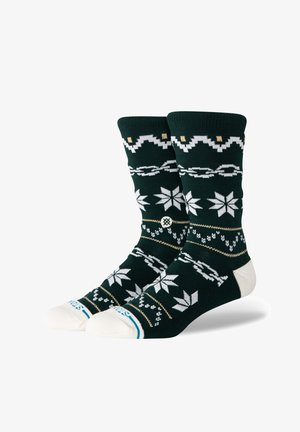 Knit socks in dark green with white and gold snowflake patterns, contrasting white toes, and a soft texture.