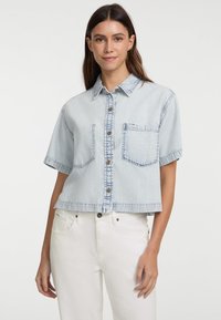 Helles, blaugraues, kurzärmeliges Denim-Hemd mit Knopfleiste, einer einzelnen Brusttasche mit sichtbaren Nähten und einem rohen Saum.