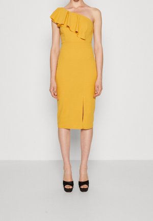 Frau trägt ein gelbes, einseitig schulterfreies, tailliertes Midikleid mit Rüschendetail und vorderlichem Schlitz, kombiniert mit schwarzen offenen High Heels.