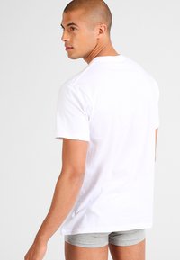 White cotton T-shirt with short sleeves, relaxed fit, and crew neckline. Smooth texture, no visible patterns, simple design.