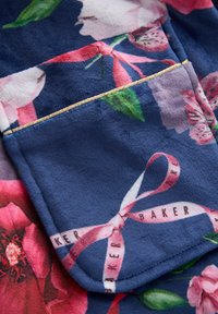 Tessuto a fantasia floreale in blu navy con accenti rosa e verdi, caratterizzato da una tasca rifinita con cucitura dorata e un dettaglio in nastro.