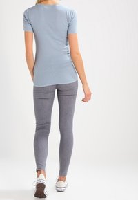 Ljusblått kortärmat topp med subtil prickig mönster, parat med grå skinny jeans och vita sneakers. Avslappnad, figurnära design.