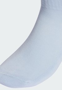 Jasnoniebieska bawełniana skarpetka o gładkiej fakturze. Posiada ściągacz w rodzaju rib oraz wzmocniony czubek, prezentując bezszwowy design w okolicy pięty.