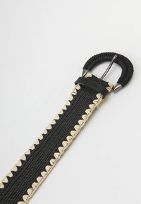 Cinturón tejido negro con acentos en crema, que presenta una hebilla de hardware redondeada. Fabricado con materiales duraderos y un acabado texturizado.
