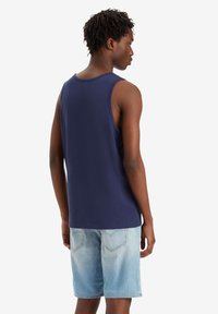 Canotta blu navy in cotone, con un design semplice e una vestibilità rilassata, abbinata a pantaloni corti in denim chiaro con un aspetto sbiadito.