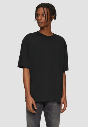 Czarna, oversize t-shirt z krótkimi rękawami i okrągłym dekoltem, wykonana z bawełny. Charakteryzuje się gładką fakturą i luźnym krojem.