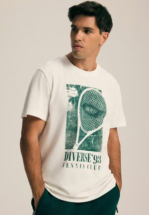 Biała bawełniana koszulka z zielonym grafiką przedstawiającą rakietę tenisową i piłkę, z napisem "DIVERSE'93 TENNIS CLUB" poniżej. Krótkie rękawy.