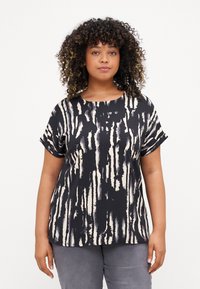 Svart og kremfarget mønstrete topp med korte ermer og rund halslinning. Stoffet har en glatt tekstur med vertikalt penselstrøk design.
