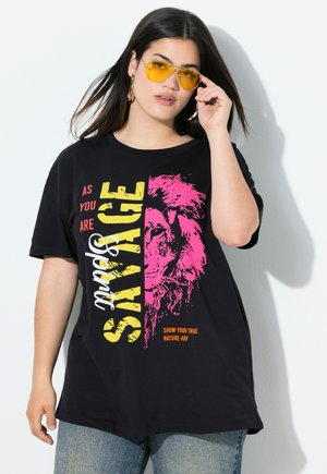 Zwarte katoenen t-shirt met gedurfde, kleurrijke tekst en een leeuwafbeelding. Het shirt heeft een losse pasvorm met korte mouwen en is gecombineerd met blauwe jeans.