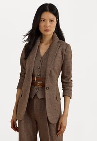 Ruskea teksturoitu bleiseri, jossa on leikkaamalla muotoiltu kaulus, yhdistettynä matching-vyöhykkeeseen ja housuihin. Korostettu ruskealla nahkavyöllä, jossa on kultaiset soljet.