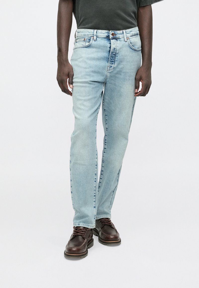 Šviesiai mėlyni tiesaus kirpimo džinsai, turintys penkias kišenes, užsegami mygtuku ir subtiliai išblukę palei kojas.