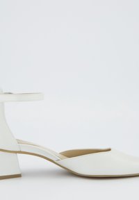 Chaussure blanche pour femme à petit talon bloc, bout pointu et bride à la cheville sur fond blanc uni.