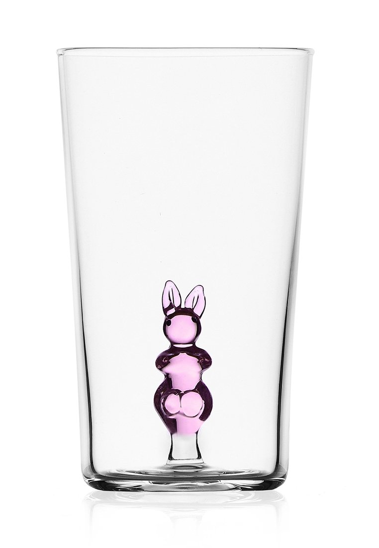 Przezroczysty szklany kubek z solidną różową figurką królika w środku. Królik ma wyolbrzymione uszy i zaokrąglone ciało, co tworzy fantazyjny wzór.