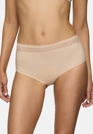 Femme portant des sous-vêtements nude sans coutures avec une ceinture en dentelle, debout devant un fond clair, montrant le torse et le haut des cuisses.