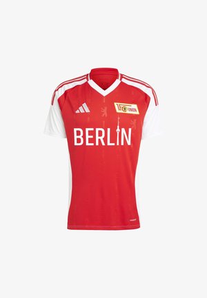 Sarkans un balts futbola krekls ar V-veida kakla dizainu, uz kura redzams uzraksts "BERLĪNE" un komandas logo. Izgatavots no viegla auduma, ar smalku rakstu.