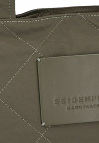 Borsa tote in tessuto trapuntato verde oliva con cuciture chiare, dotata di un'etichetta in leather rettangolare impressa con "SEIDENFADEN MANUFAKTUR."