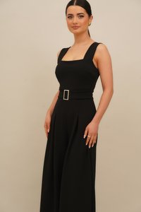 Melna kombinezons ar kvadrātu izgriezumu, platām siksnām un jostu ar kvadrātu sprādzi, izgatavots no gludas auduma ar piegriezto fit.