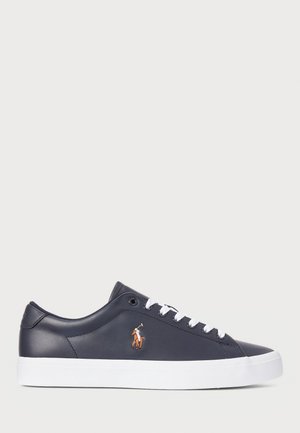Lage sneaker van marineblauw leer met witte veters, witte zool en geborduurd bruin polo-spelerlogo aan de zijkant.