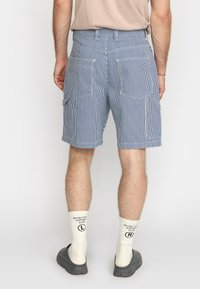 Blauwe en witte gestreepte cargoshorts met meerdere zakken, van katoen, met een ontspannen pasvorm, gecombineerd met grijze schoenen en witte sokken met logo.