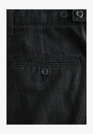 Dark pinstripe fabric with a buttoned welt pocket and two buttons along the waistband of a tailored garment.