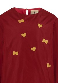 Robe rouge avec un col rond, ornée de broderies en forme de cœur et de nœud dorés. Fermeture au dos avec un petit bouton. Texture lisse.