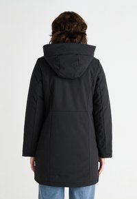 Cappotto lungo nero con cappuccio, caratterizzato da una texture liscia, taglio dritto e dettagli di cucitura discreti sulla schiena. Ideale per il clima freddo.