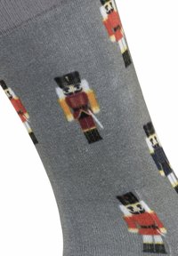 Calzini grigi con design di schiaccianoci in rosso, nero e giallo. Texture a maglia piatta con spessore medio, adatti per abbigliamento casual.