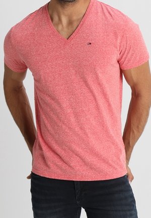 Vaaleanpunainen v-kaula-aukon t-paita, jossa on sekoitekangas. Lyhyet hihat, hieman tekstuuri, ja pieni logo vasemmalla rinnalla.