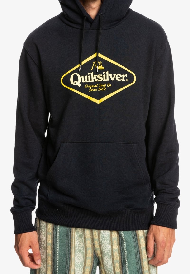 Sudadera azul marino con un gran logo de diamante amarillo y el texto "Quiksilver", capucha con cordones y bolsillo frontal. Tejido suave con puños acanalados.