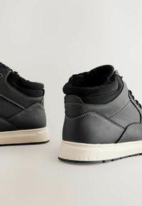 Schwarze High-Top-Schuhe mit Lederobermaterial, gepolstertem Schaftrand, weißer Zwischensohle und Gummisohle; mit kontrastierenden Nähten und Schnürung.