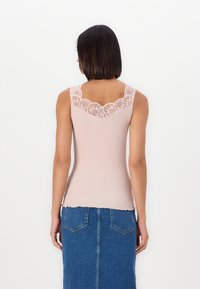 Ribbed, light pink tank top with a lace trim along the neckline; paired with a blue denim skirt featuring back pockets and a straight cut.