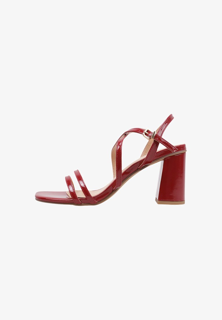 Sandalias de tacón alto de charol rojo con punta cuadrada, múltiples tiras, cierre con hebilla en el tobillo y un tacón grueso.