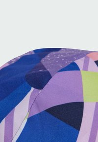 Multicolored fabric featuring geometric patterns in shades of blue, purple, green, and pink with a smooth texture and visible stitching detail.