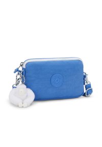 Borsa a tracolla blu con zip bianca, patch con logo Kipling e portachiavi a forma di piccolo gorilla di peluche bianco attaccato.