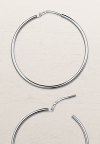 Silberne Creolen mit einem eleganten, kreisförmigen Design. Das Metall ist glänzend, verfügt über einen Scharnierverschluss und eine glatte Textur.