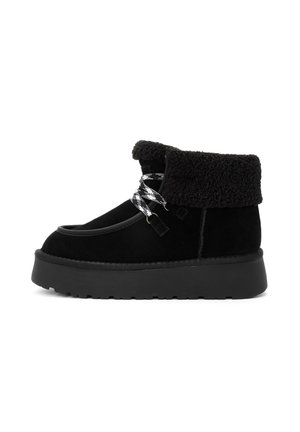 Schwarze Wildleder-Stiefeletten mit einem strukturierten Fellaufschlag, ausgestattet mit einer dicken schwarzen Sohle und gemusterten schwarz-weißen Schnürsenkeln.