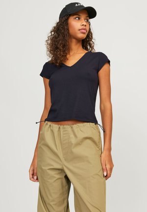 Black ribbed short-sleeve V-neck top with a cropped design and adjustable drawstring at the hem, paired with light khaki elastic waist pants.