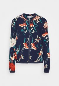 Blommig zip-up jacka i marinblått tyg, med livfulla blommor i rött, vitt och grönt, samt ribbad krage och muddar.