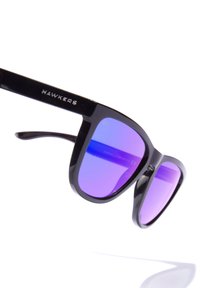 Black sunglasses with square frames, purple gradient lenses, and "HAWKERS" logo on the temple. Smooth plastic material and sleek design.